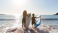 iStock-1203187750 (1).jpg Rear View Of Two Children Wearing Wetsuits Running Into Sea With Bodyboards On Beach Vacation