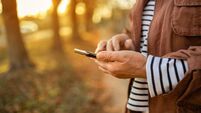 Woman-using-mobile-generic-scam-text-message.jpg woman hand holding mobile cellphone, reading news or watching online having video call using mobile application. Beautiful autum
