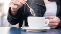 MWNTR0 The woman stirs a spoonful of coffee and tea. The woman will sweeten her coffee with sugar. Misuse of sugar, use of sweeteners.