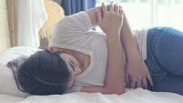 2HAT4WM Woman lying on bed, suffering from strong stomach pain, endometriosis, menstruation.