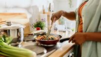 iStock-1477430966 healthy eating.jpg Woman preparing quinoa vegetable mix cooked in a frying pan