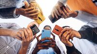 iStock-1371958166.jpg Teens in circle holding smart mobile phones - Multicultural young people using cellphones outside - Teenagers addicted to new te