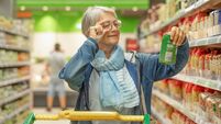 iStock-1407284964.jpg Portrait smiling senior woman making purchases in the supermarket selecting checking a product. Caucasian elderly customer in gr