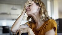 iStock-1321004785.jpg Portrait of crying woman with hands on her face while sitting indoors