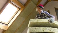 iStock-873936804.jpeg Man installing thermal roof insulation layer - using mineral wool panels. Attic renovation and insulation concept