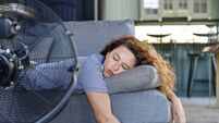 Summer sleep iStock-2167520887.jpg Young woman lying in front of the electric fan at home, overwhelmed by the heat