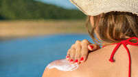 GD034D Young woman applying sun lotion on summer vacation