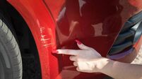 iStock-1485759641.jpg Scratches on the front bumper of a red car. A young girl driver got into a traffic accident and turns to a repair service.