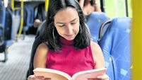 1497240880 Young woman reading a book while commuting by bus