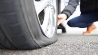 tyre extinguishers 0723.jpg man touching a flat tire on the roadside