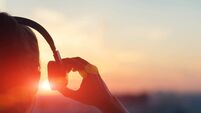 iStock-958364166.jpg Girl in headphones listening to music in the city at sunset