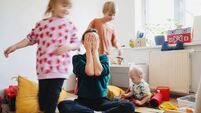 iStock-1835186835.jpg Stressed out mother sitting on floor while children running around her.