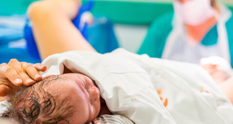 P0FWK9 Cute newborn baby boy just after childbirth and doctor in the background