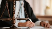 iStock-1643971176.jpg Closeup, scales and law on table, office and attorney man in blurred background with reading for crime analysis. Advocate, lawye