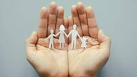 domestic abuse 3.jpg Hand holding family paper cut on blue background. Family day concept, foster care, domestic violence, homeschool, international