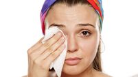 iStock-996001528.jpg a young, pretty woman wipes her face with a wet wipe on a white background