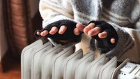 Cold winter.jpg Person heating their hands at home over a domestic portable radiator in winter